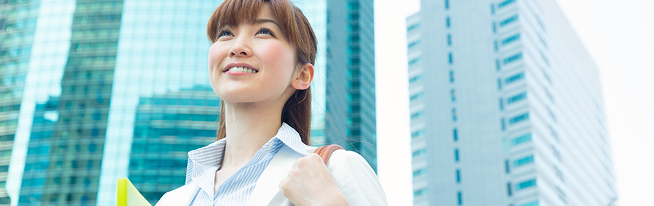 ビジネス街を笑顔で闊歩する女性ビジネスマンの写真